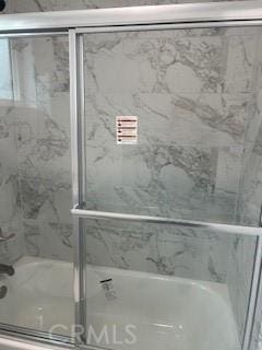 bathroom featuring combined bath / shower with glass door