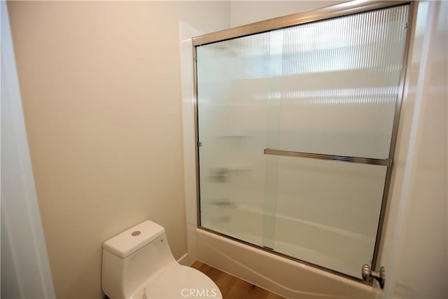 bathroom with toilet, combined bath / shower with glass door, and hardwood / wood-style flooring