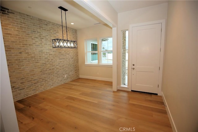 foyer with brick wall and light wood-type flooring