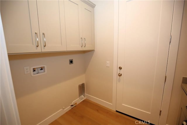 clothes washing area with cabinets, hookup for a washing machine, electric dryer hookup, light hardwood / wood-style floors, and hookup for a gas dryer