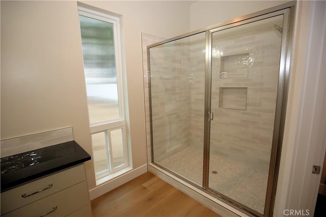 bathroom with hardwood / wood-style floors, vanity, and a shower with door