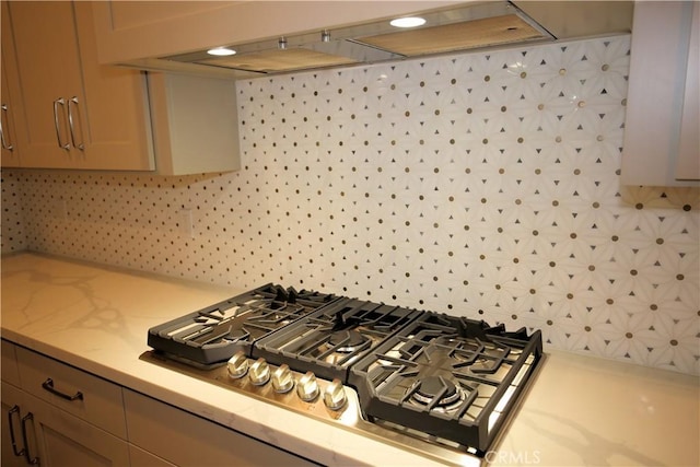 interior details featuring stainless steel gas stovetop, backsplash, and extractor fan