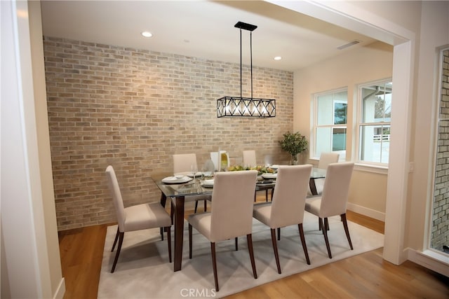 dining area with light hardwood / wood-style flooring and brick wall