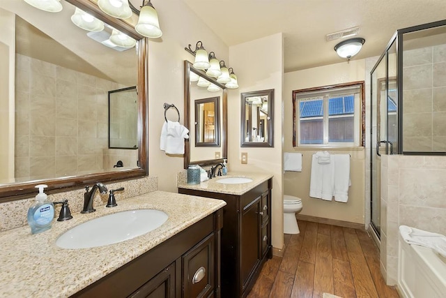 bathroom with a shower with door, vanity, wood-type flooring, and toilet