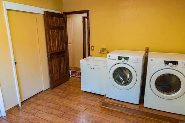 laundry area featuring separate washer and dryer, light hardwood / wood-style floors, cabinets, and sink