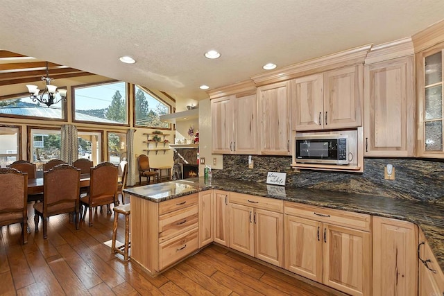 kitchen with lofted ceiling with beams, dark hardwood / wood-style flooring, kitchen peninsula, and decorative light fixtures