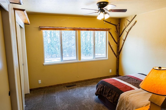 carpeted bedroom with multiple windows, ceiling fan, and a textured ceiling