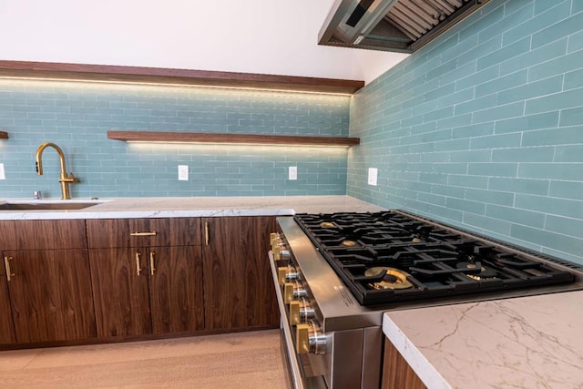 kitchen featuring backsplash, custom range hood, sink, and stainless steel range with gas stovetop