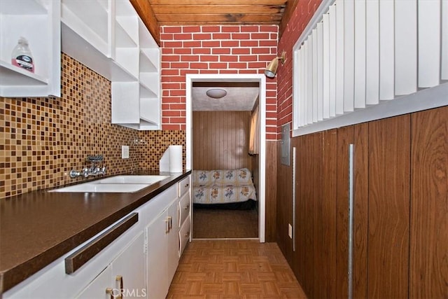 kitchen featuring light parquet floors, white cabinets, sink, and tasteful backsplash