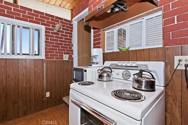 kitchen with parquet flooring, wooden walls, brick wall, and white appliances