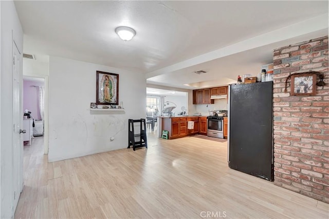 kitchen featuring black refrigerator, stainless steel range oven, light wood-type flooring, and kitchen peninsula