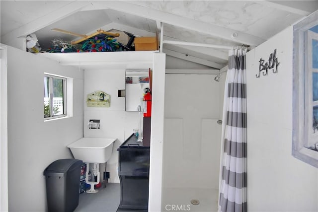 bathroom with curtained shower, lofted ceiling, and concrete flooring