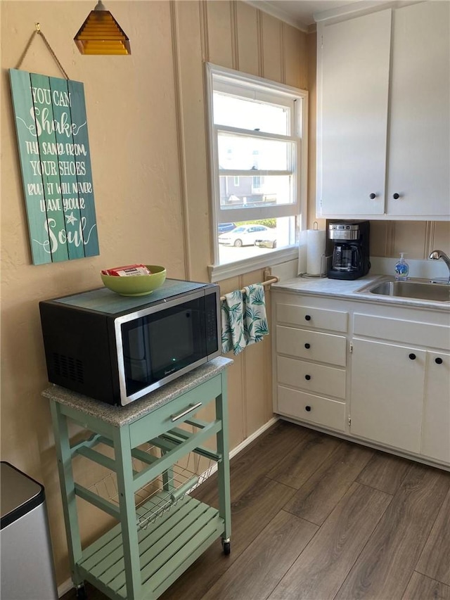 kitchen with dark hardwood / wood-style flooring, white cabinetry, and sink