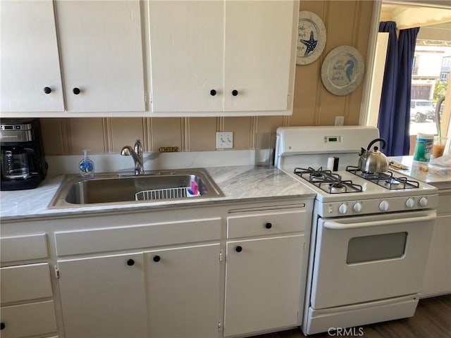 kitchen featuring sink, white cabinetry, white gas range oven, and dark wood-type flooring