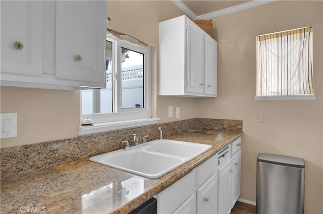 kitchen featuring light stone countertops, white cabinetry, sink, and crown molding