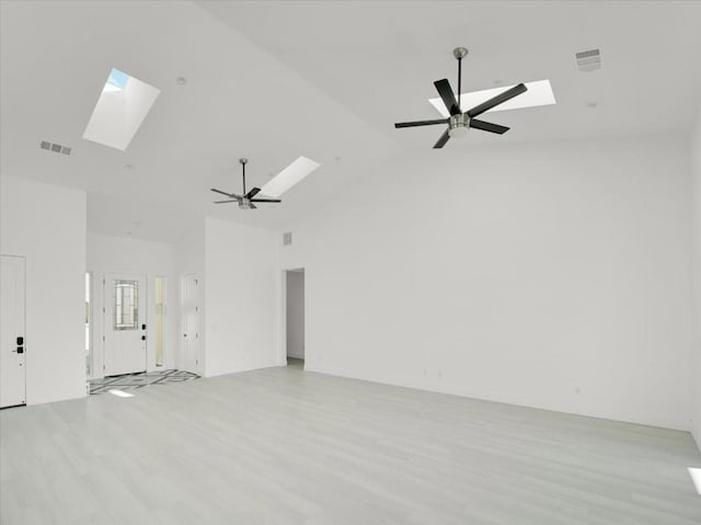 unfurnished room with high vaulted ceiling, ceiling fan, a skylight, and light hardwood / wood-style flooring