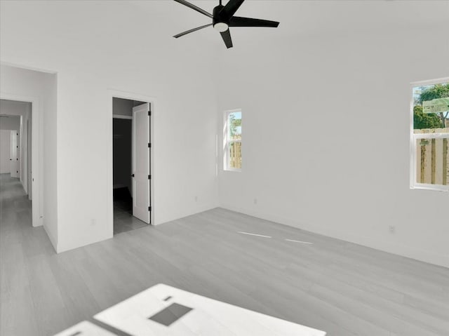 unfurnished room with ceiling fan, a towering ceiling, and light hardwood / wood-style floors