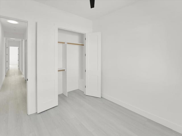 unfurnished bedroom featuring light wood-type flooring, ceiling fan, and a closet