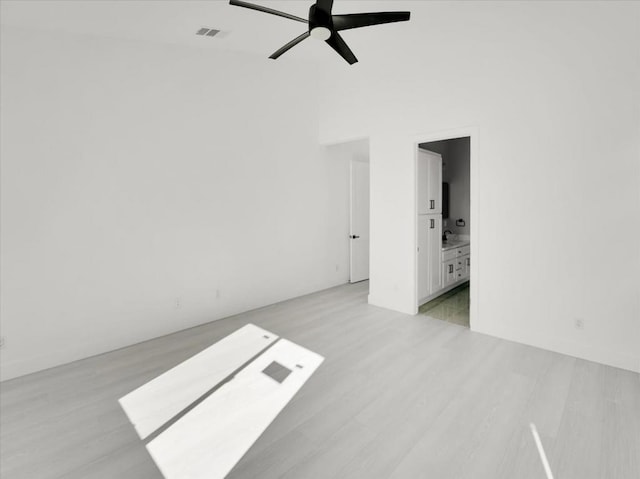 spare room featuring ceiling fan, light hardwood / wood-style flooring, and a towering ceiling