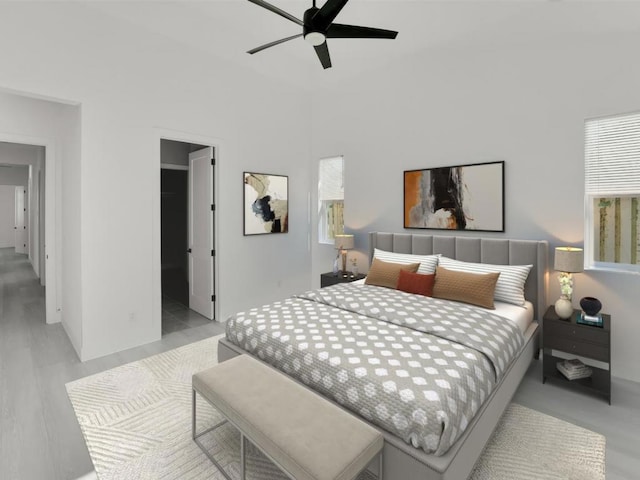 bedroom featuring ceiling fan, ensuite bath, multiple windows, and light hardwood / wood-style flooring