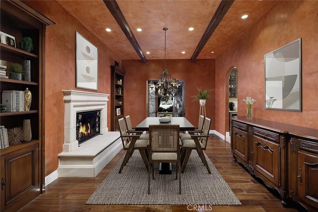 dining area with dark wood-type flooring, a notable chandelier, and built in shelves