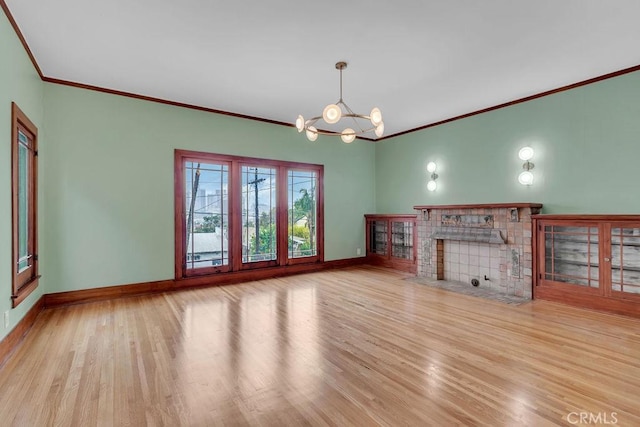 unfurnished living room featuring light wood-type flooring, ornamental molding, and an inviting chandelier