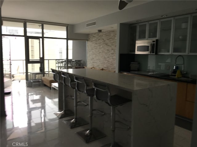 kitchen with a breakfast bar, tasteful backsplash, stone counters, and sink