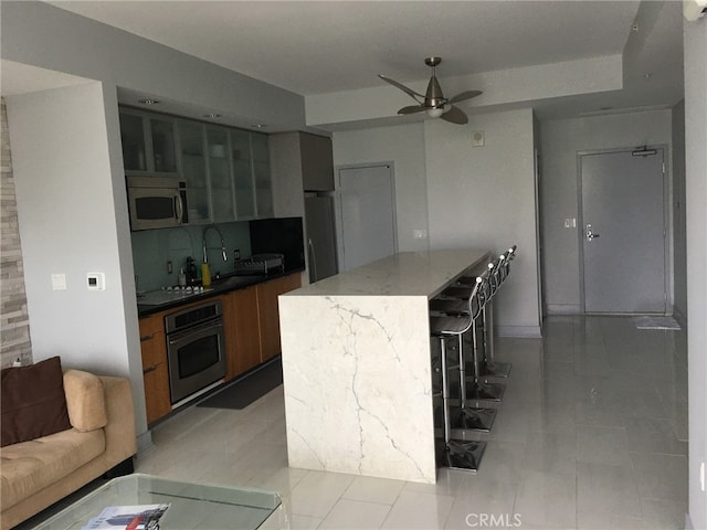 kitchen with decorative backsplash, a kitchen island, light tile patterned flooring, and stainless steel appliances