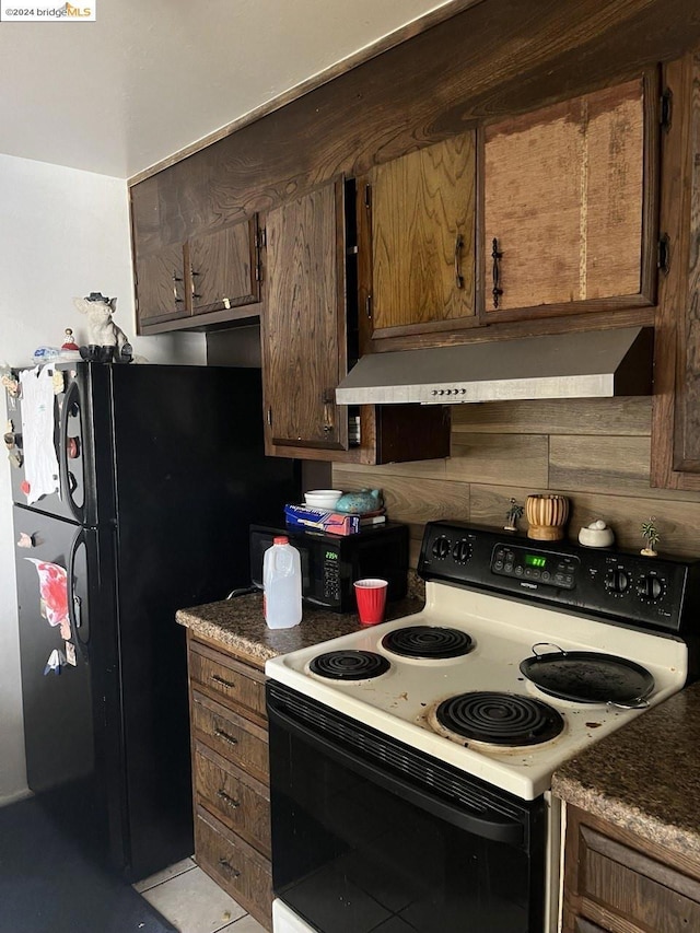 kitchen with black refrigerator, light tile patterned floors, dark brown cabinetry, and white range with electric stovetop