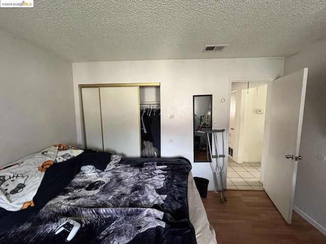 bedroom featuring a textured ceiling, hardwood / wood-style flooring, and a closet