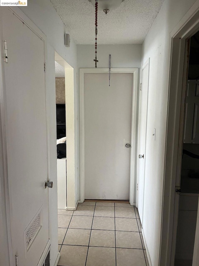 hall with light tile patterned floors and a textured ceiling