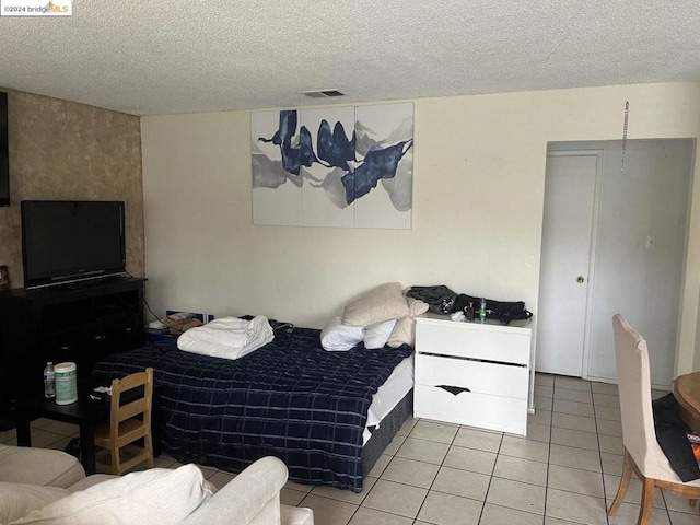 bedroom featuring light tile patterned floors and a textured ceiling