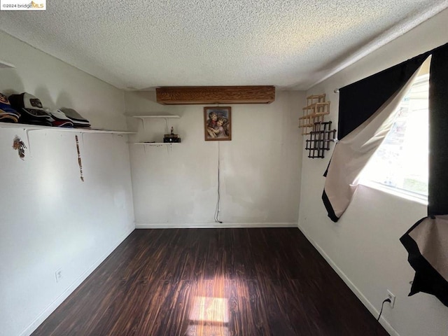 spare room featuring dark hardwood / wood-style flooring and a textured ceiling