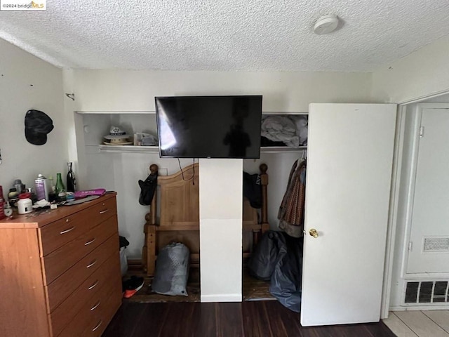 bedroom with a closet, dark wood-type flooring, and a textured ceiling