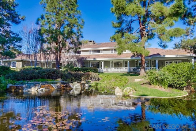 rear view of house with a water view and covered porch