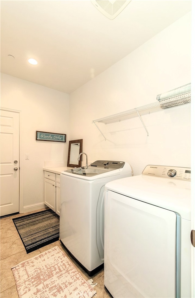 washroom featuring light tile patterned flooring, washing machine and dryer, and cabinets