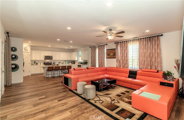 living room with light wood-type flooring and ceiling fan