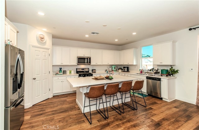 kitchen featuring a kitchen island, appliances with stainless steel finishes, dark hardwood / wood-style floors, and white cabinetry