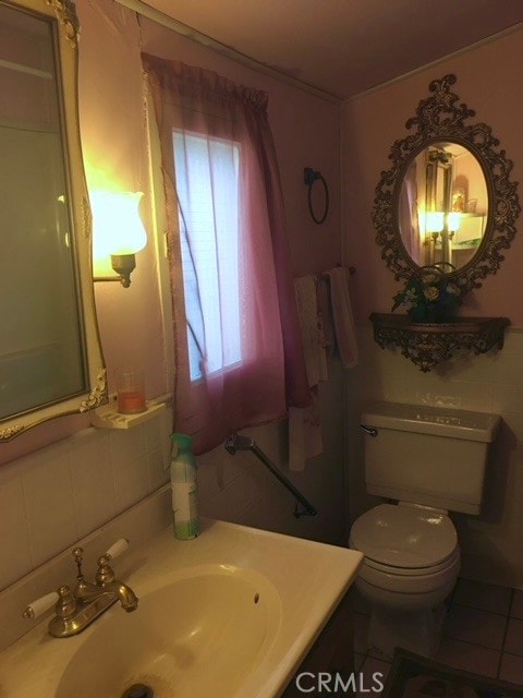 bathroom featuring vanity, tile walls, tile patterned flooring, and toilet