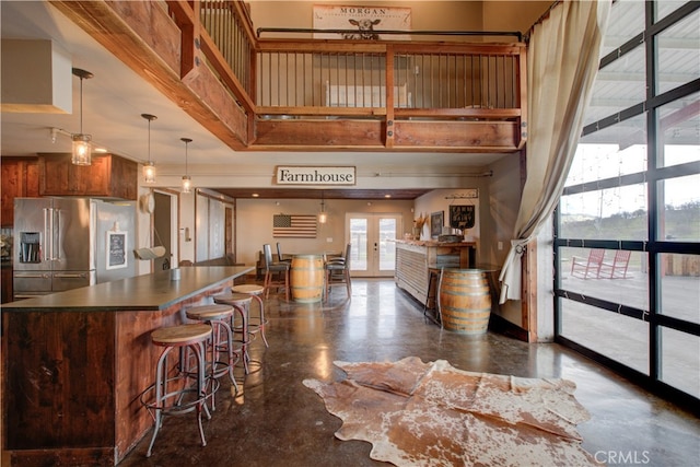 kitchen featuring french doors, a towering ceiling, pendant lighting, and high end fridge