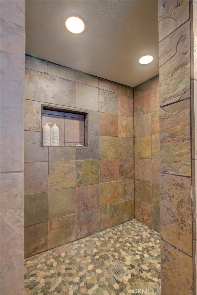 bathroom featuring a tile shower and a textured ceiling