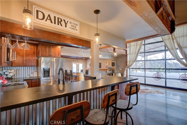 kitchen featuring decorative backsplash, hanging light fixtures, a kitchen bar, concrete flooring, and stainless steel appliances