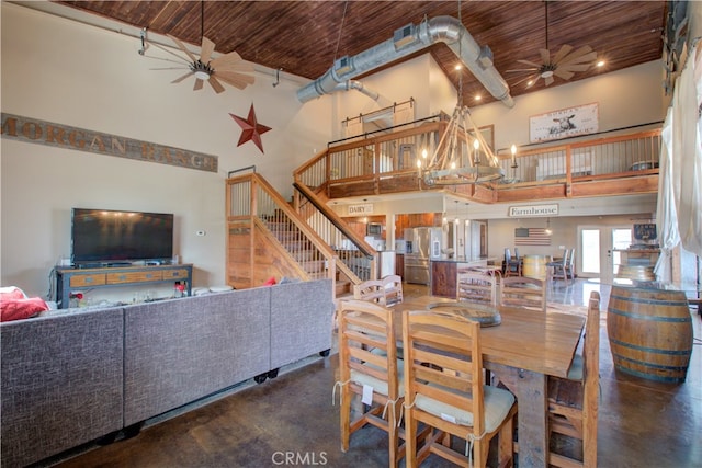 dining area with a high ceiling, wood ceiling, ceiling fan with notable chandelier, and concrete floors