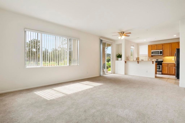 unfurnished living room featuring light carpet, a healthy amount of sunlight, and ceiling fan