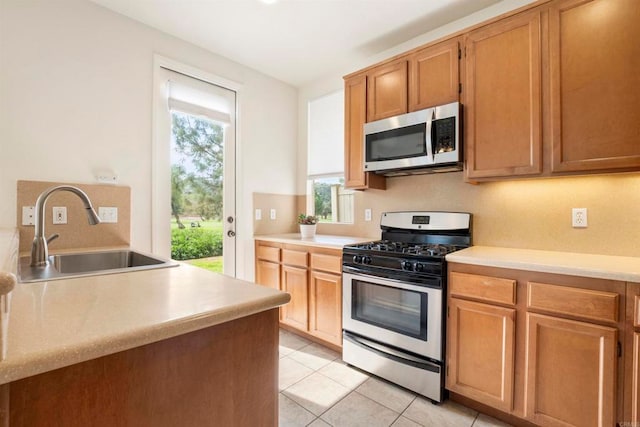 kitchen with light tile patterned floors, stainless steel appliances, sink, and plenty of natural light