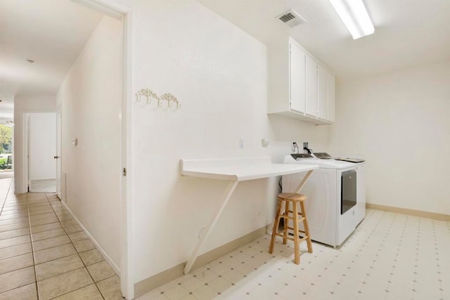 clothes washing area with washing machine and dryer and cabinets