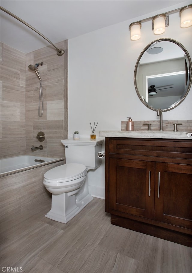 full bathroom with tiled shower / bath combo, vanity, and toilet