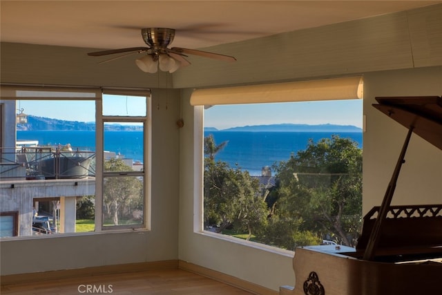 interior space featuring hardwood / wood-style floors, a water and mountain view, and ceiling fan