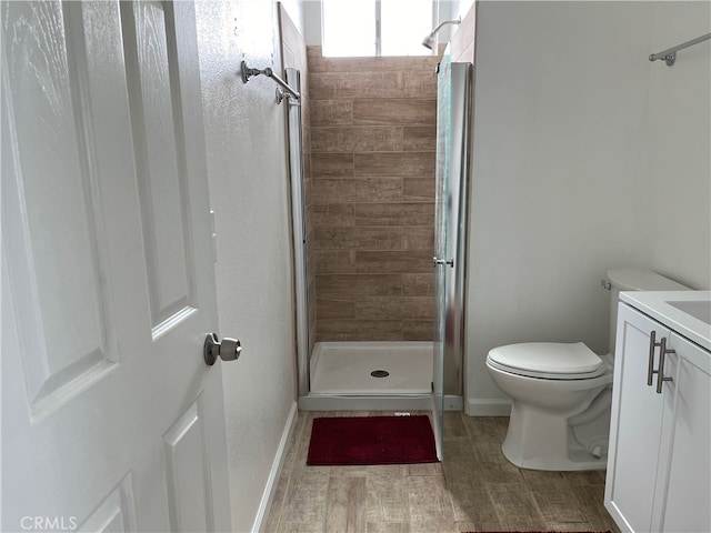 bathroom with vanity, tiled shower, hardwood / wood-style flooring, and toilet