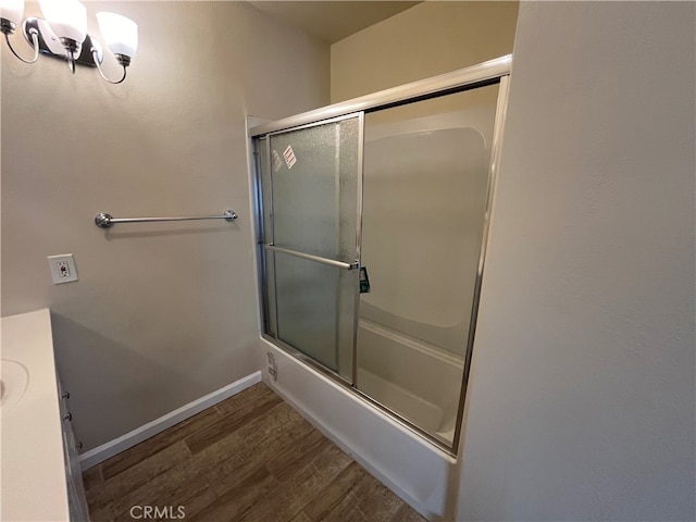 bathroom with bath / shower combo with glass door, hardwood / wood-style floors, and vanity